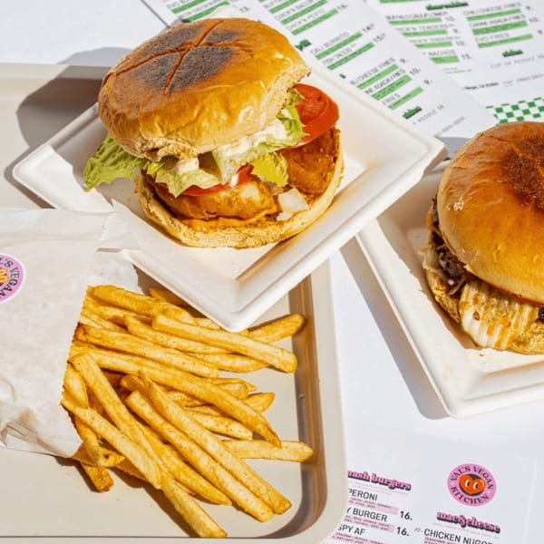 Two vegan burgers and a side of fries from Val's Vegan Kitchen on a white tray.